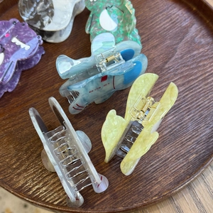 Macro detail of colorful acetate hair claws in cute alien and animal shapes on wood