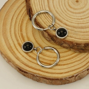 Vue détaillée des boucles d'oreilles créoles en acier avec pierre noire et texture torsadée