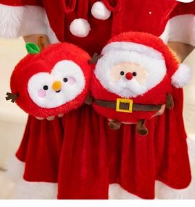 Close-up of plush Santa Claus and festive apple bird dolls held against a red background