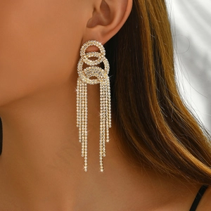Macro detail of long gold tassel earrings with sparkling rhinestones worn by a model