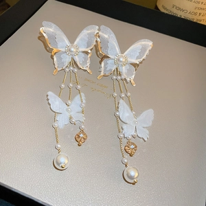Detail of elegant butterfly tassel earrings with white lace, pearls and amber beads