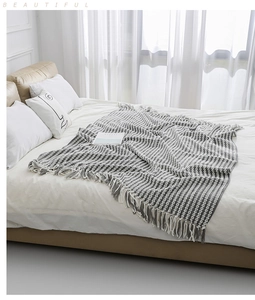 Detail of hand-knitted chenille blanket featuring grey stripes and decorative fringe trim