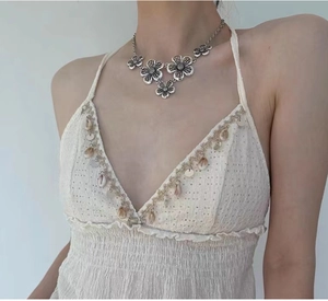 Detail of bohemian silver floral necklace worn with white shell-fringed top
