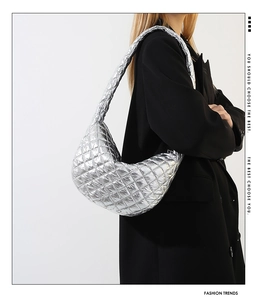 Close-up of metallic silver quilted shoulder bag with wide strap on black blazer