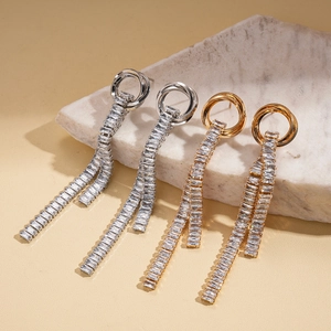 Elegant gold and silver tassel earrings with rectangular zircons on marble stone