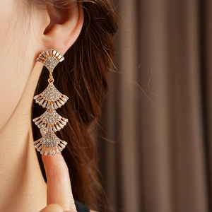 Close-up of elegant gold layered fan-shaped tassel earrings with sparkling rhinestones