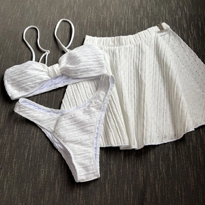 Detailed macro view of white seersucker three-piece bikini set with textured fabric and mini skirt