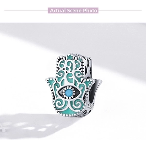 Macro shot of S925 sterling silver Hamsa Hand charm with green enamel and blue gemstone