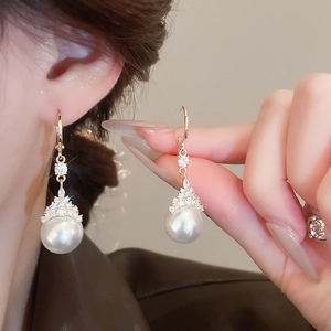 Détail de boucles d'oreilles pendantes plaquées or avec perles rondes et zircons