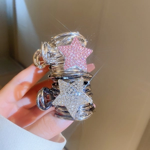 Close-up of sparkling star-shaped claw clips with pink and white rhinestones in hand