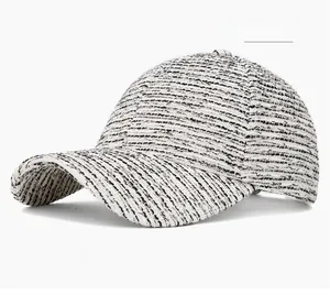 Detailed view of an off-white tweed baseball cap featuring a textured woven pattern