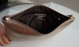 Detail shot of champagne crocodile pattern envelope clutch showing inner lining and pocket