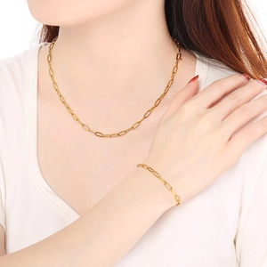 Close-up of a gold stainless steel paperclip chain necklace and bracelet on a model