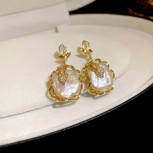 Détail de boucles d'oreilles fleur en perles baroques avec plaqué or et cristaux brillants