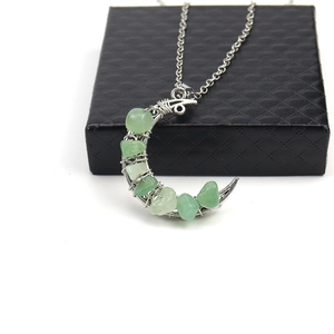 Silver crescent moon necklace with green chakra crystal stones on black jewelry box