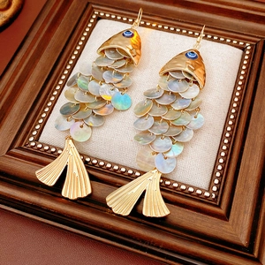 Detailed shot of vintage fish drop earrings with iridescent shell scales in a wooden frame