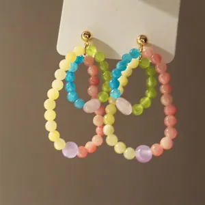 Detailed close-up of colorful beaded double hoop earrings with a gold stud fastening