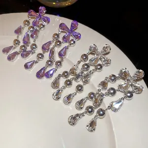 Elegant silver tassel earrings with purple and clear teardrop crystals in a ceramic dish