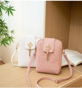 Detail of small crossbody phone bags with embossed patterns, crown decor, and tassels