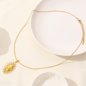 Detailed view of gold stainless steel sunburst pendant on O-chain with lobster clasp
