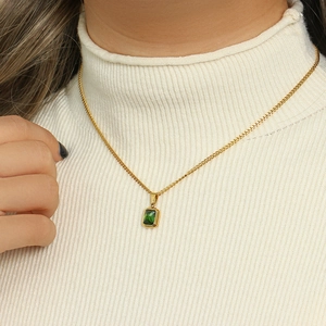Detail of a green rectangular gemstone pendant on a gold chain over a white sweater