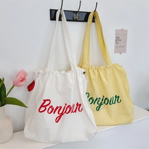 Detail of canvas shoulder bags with drawstring closure and Bonjour lettering