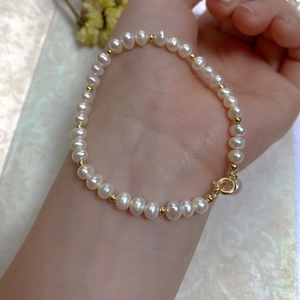 Macro detail of natural freshwater pearl bracelet with gold beads and spring ring clasp