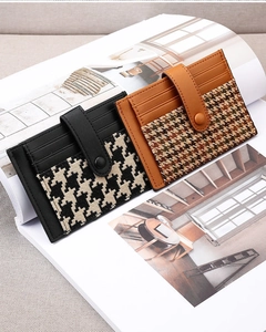 Detail view of houndstooth leather card holders with snap button strap on a magazine