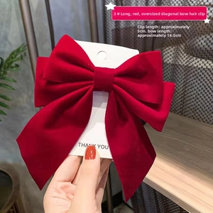 Detail of red oversized bow hair clip with velvet texture showing 14.5cm size dimension