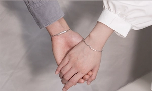 Close-up of matching silver couple bracelets on hands for Valentine's Day gift