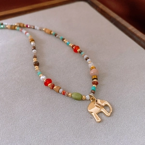 Detailed shot of vintage elephant pendant and colorful stone beads on gray fabric