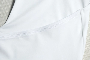 Close-up of white knitted dress showing high-quality double-stitch sewing and fabric texture