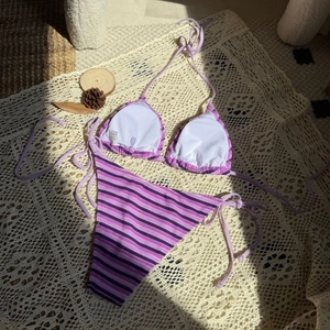 Dettaglio in piano del bikini a righe viola con tessuto a maglia e laccetti laterali