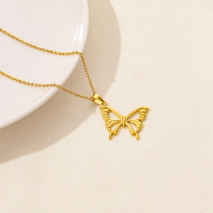 Elegant gold butterfly pendant necklace on a minimalist ceramic plate background