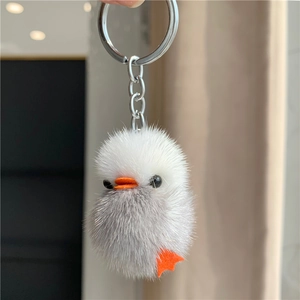 Detailed close-up of a white and grey plush duck keychain with soft faux fur texture