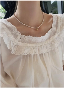Close-up of baby freshwater pearl choker necklace with a gold heart pendant and lace top