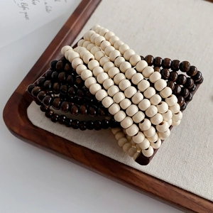 Detail of layered coconut shell and wood bead bracelets in beige and dark coffee tones