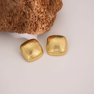 Golden square stud earrings with vertical striped texture on a natural stone base