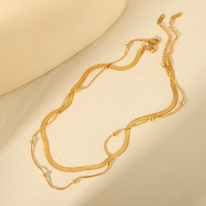 Elegant gold double layer necklace featuring snake chain and bead chain on beige background