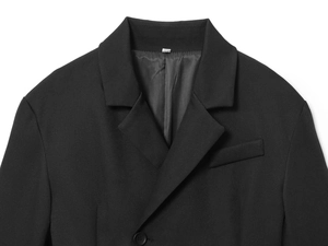 Detailed view of black blazer lapels and single button on smooth woven fabric