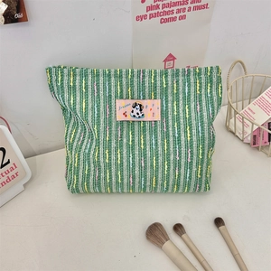 Détail d'une trousse de maquillage tissée rayée verte et blanche avec écusson chiot mignon