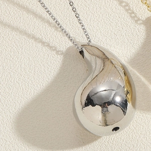 Detail of silver water-drop pendant with mirror-polished surface on textured background