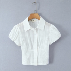 Close-up of a white slim-fit polo top featuring textured jacquard and puff sleeves
