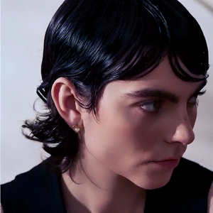 Fashionable 18k gold heart pearl earrings worn by a model in a close-up profile view