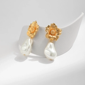 Detailansicht goldener Blumenohrringe mit hängenden weißen Barockperlenanhängern