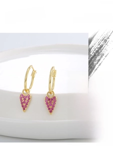 Detailed macro view of gold plated heart earrings with purple cubic zirconia stones