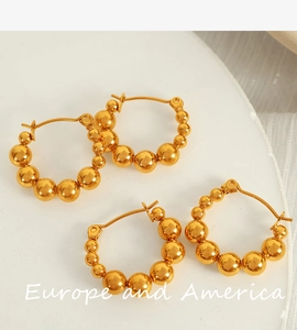 Close-up of golden beaded hoop earrings on a white stone background for a luxury aesthetic