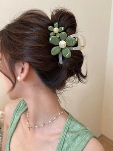 Detail einer grünen Organza-Blüten-Haarklammer mit Perlen auf braunem Haar