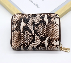 Macro shot of faux leather wallet featuring python print and gold metal zipper closure