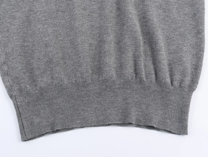 Close-up of gray knit cardigan featuring ribbed hem and detailed fabric texture
